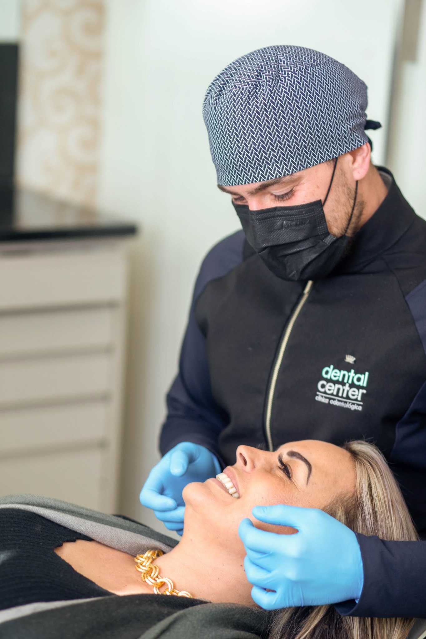 Profissional com máscara atendendo paciente em cadeira odontológica